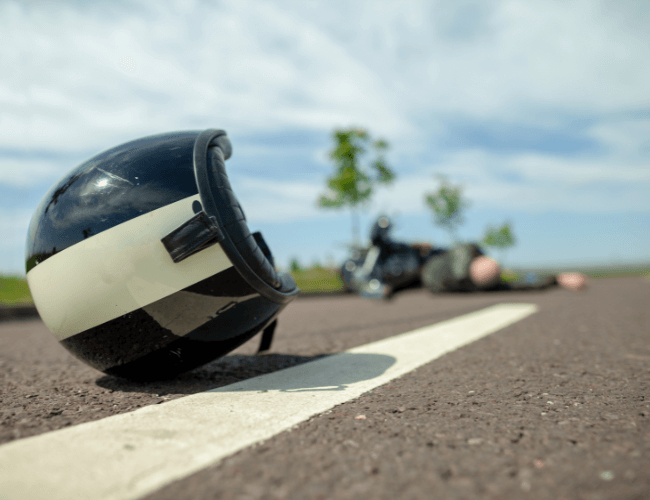 biker helmet lies on street near a motorcycle accident near a person suggesting an aggravation of a pre-existing condition settlement